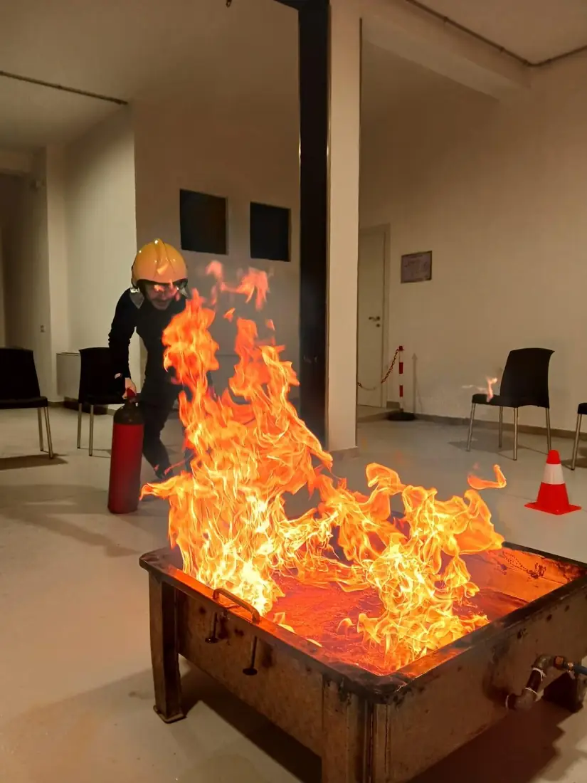 Un partecipante spegne un focolaio con un estintore durante l’esercitazione antincendio