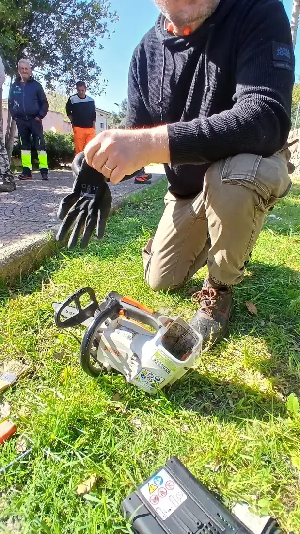Un partecipante controlla la motosega a terra con i guanti da lavoro, prima dell’uso